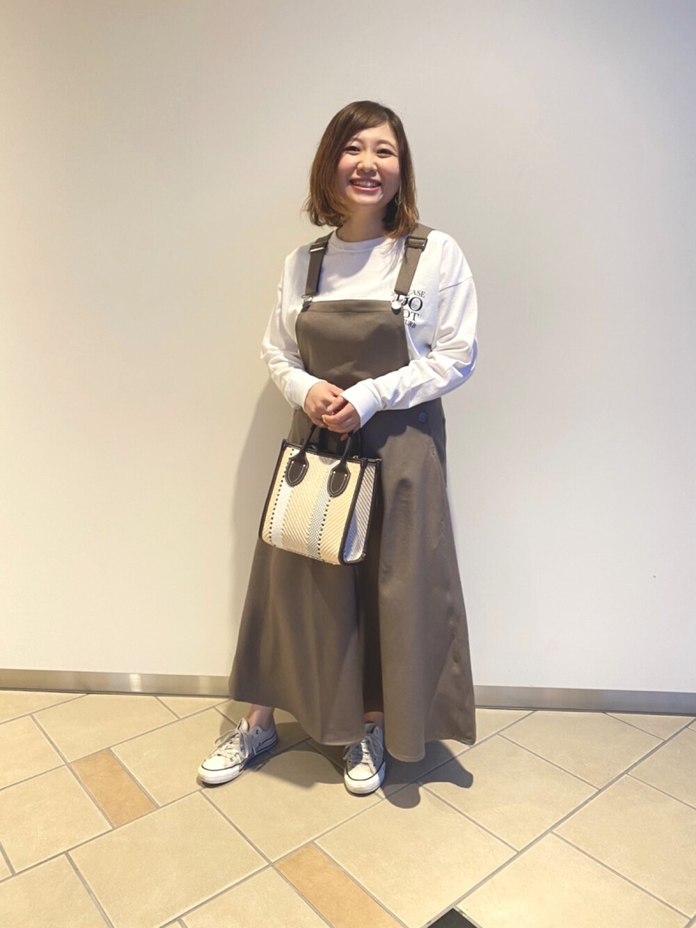ホワイト系のTシャツ/カットソー、ブラウン系のトートバッグを着用したレディースの春コーディネートの1枚目の写真