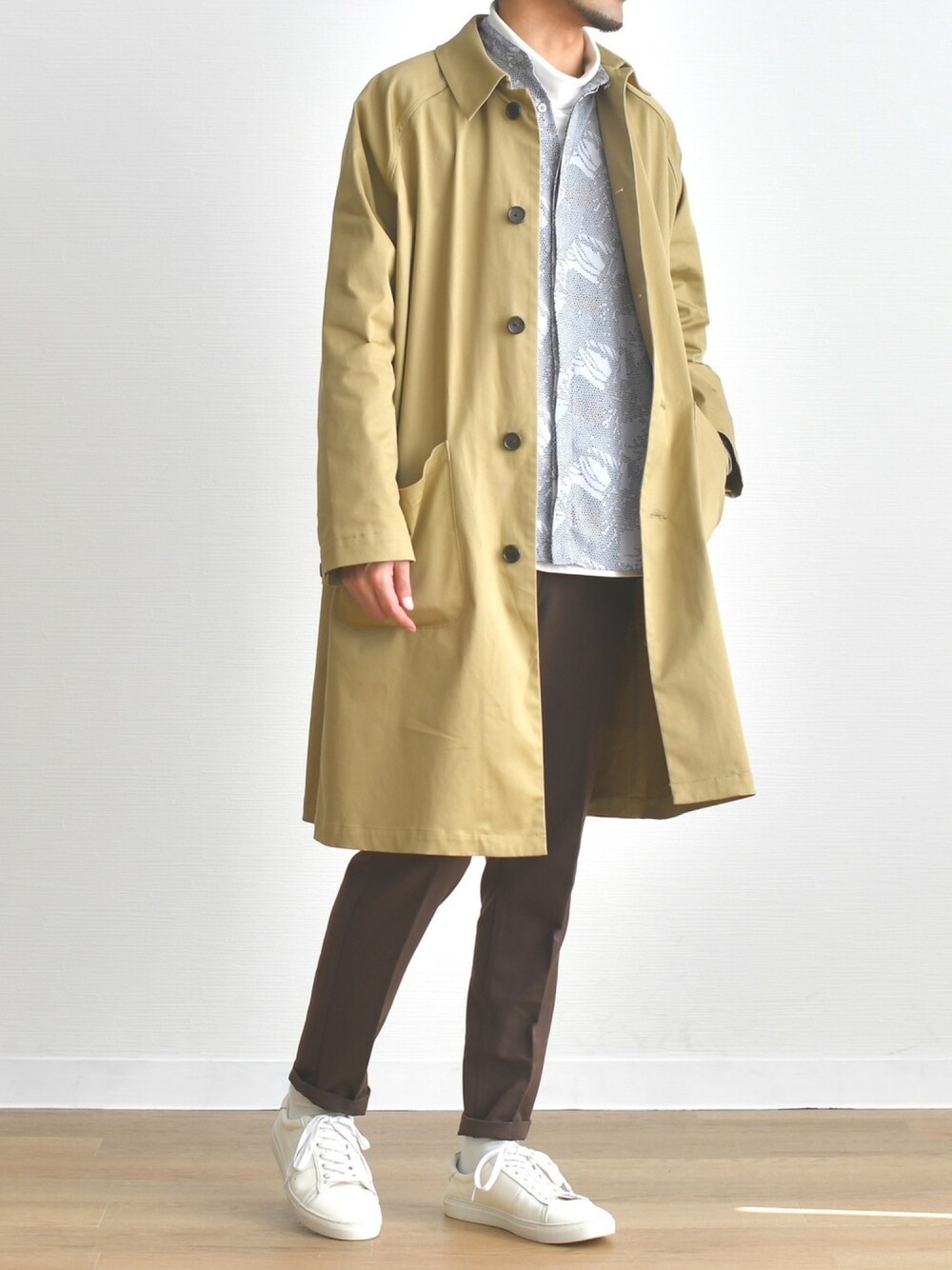 ベージュ系のステンカラーコート、グレー系のシャツ/ブラウス、ホワイト系のTシャツ/カットソーを着用したメンズの春コーディネートの1枚目の写真