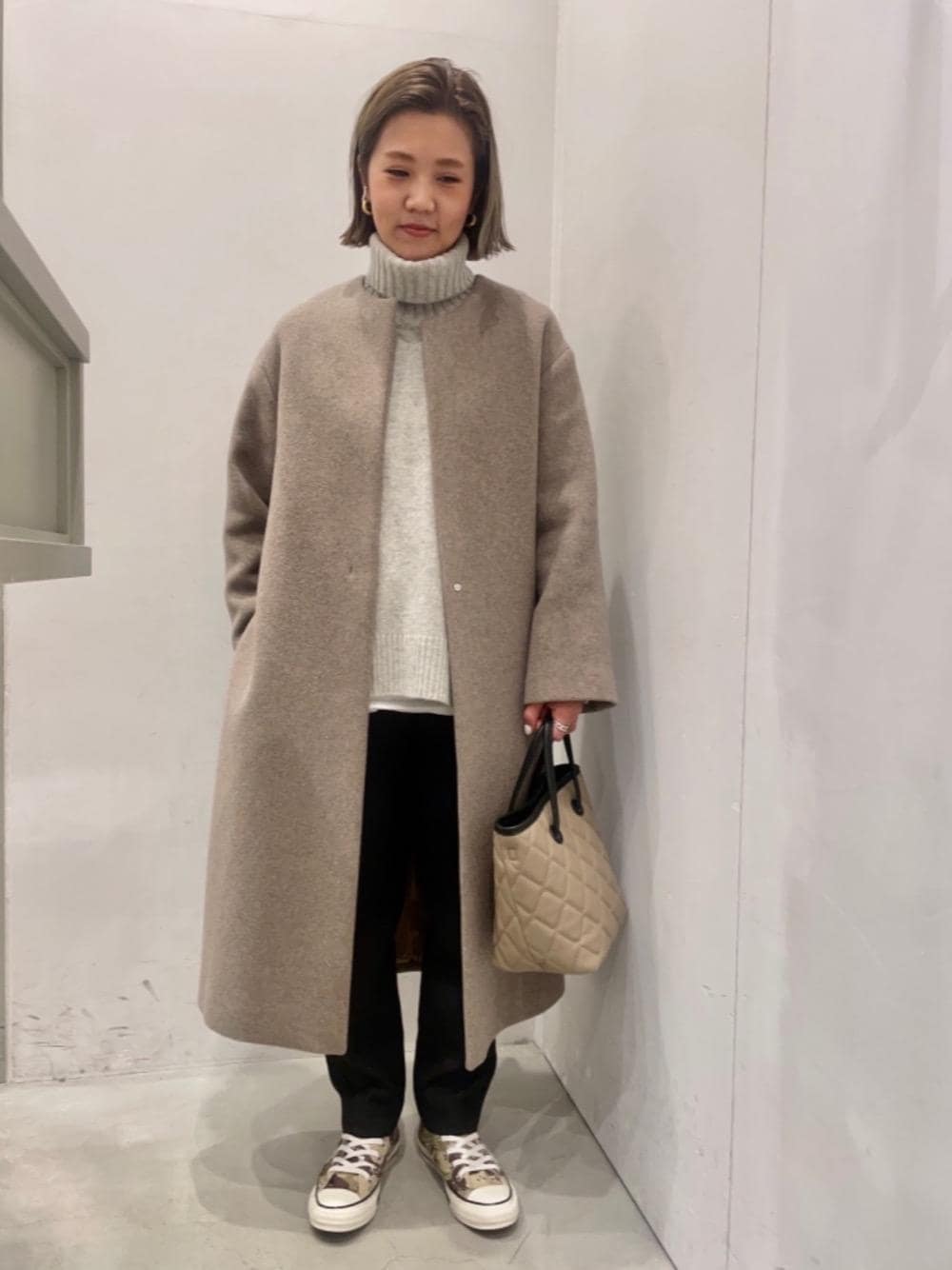 グレー系のニット/セーター、ブラウン系のノーカラーコート、ブラウン系のトートバッグを着用したレディースの冬コーディネートの1枚目の写真