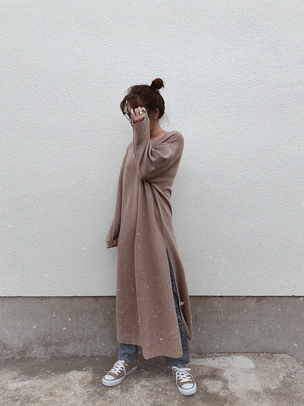 ベージュ系のワンピース、ブルー系のデニムパンツ、ブラウン系のスニーカーを着用したレディースの冬コーディネートの1枚目の写真