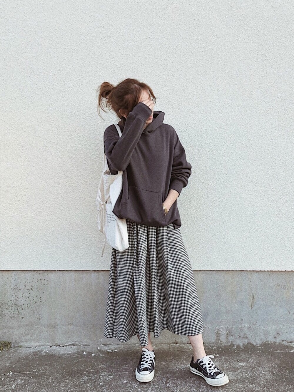 ブラック系のパーカー、ブラック系のスカート、ブラック系のスニーカーを着用したレディースの秋コーディネートの1枚目の写真