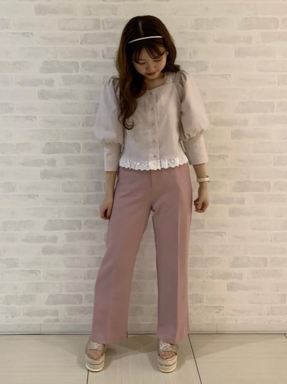 ピンク系のスラックス、ゴールド系のサンダル、ホワイト系のタンクトップを着用したレディースの夏コーディネートの1枚目の写真