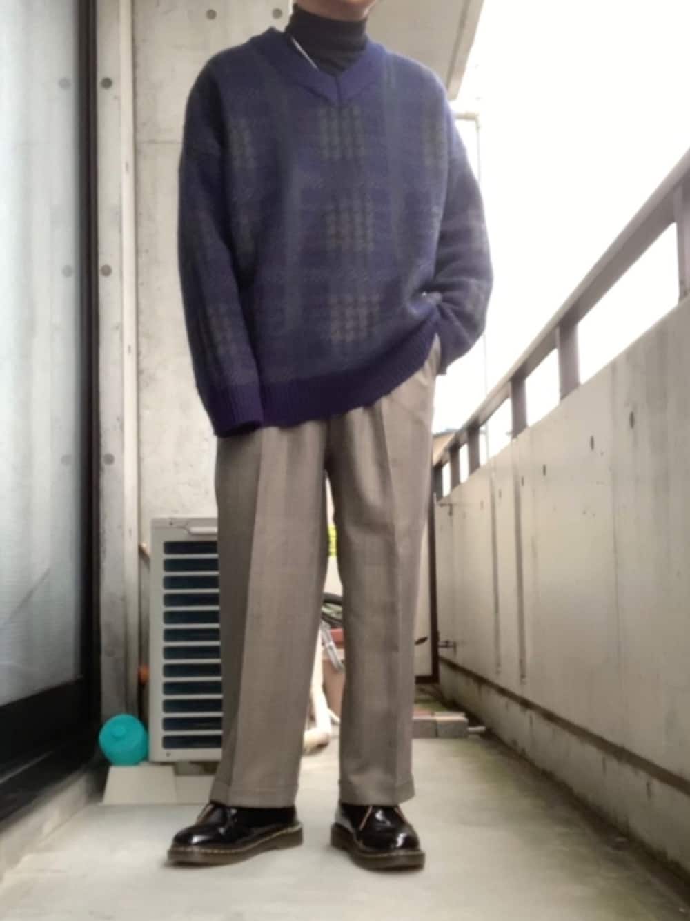 グリーン系のニット/セーター、グレー系のスラックス、ブラック系のブーツを着用したメンズの冬コーディネートの1枚目の写真