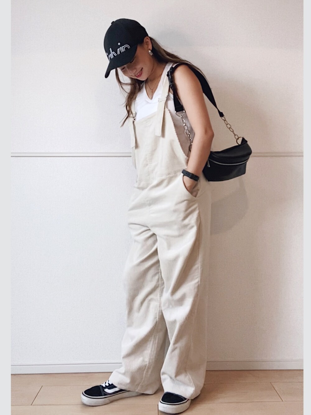 ブラック系のボディバッグ/ウエストポーチ、ブラック系のスニーカー、ホワイト系のサロペット/オーバーオールを着用したレディースの秋コーディネートの1枚目の写真