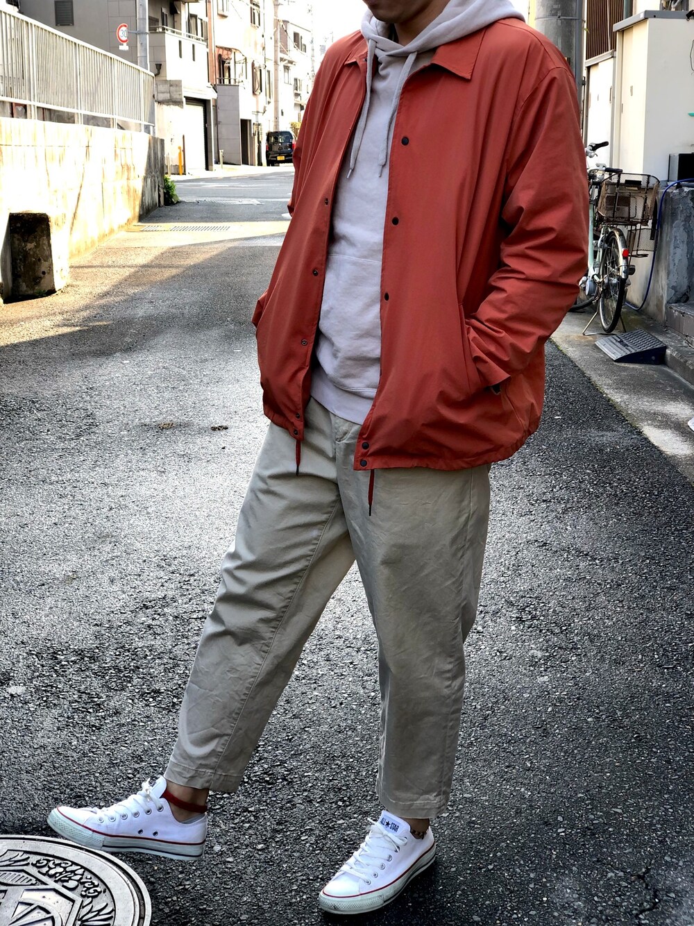 ベージュ系のチノパンツ、ベージュ系のパーカー、レッド系のカバーオールを着用したメンズの春コーディネートの1枚目の写真