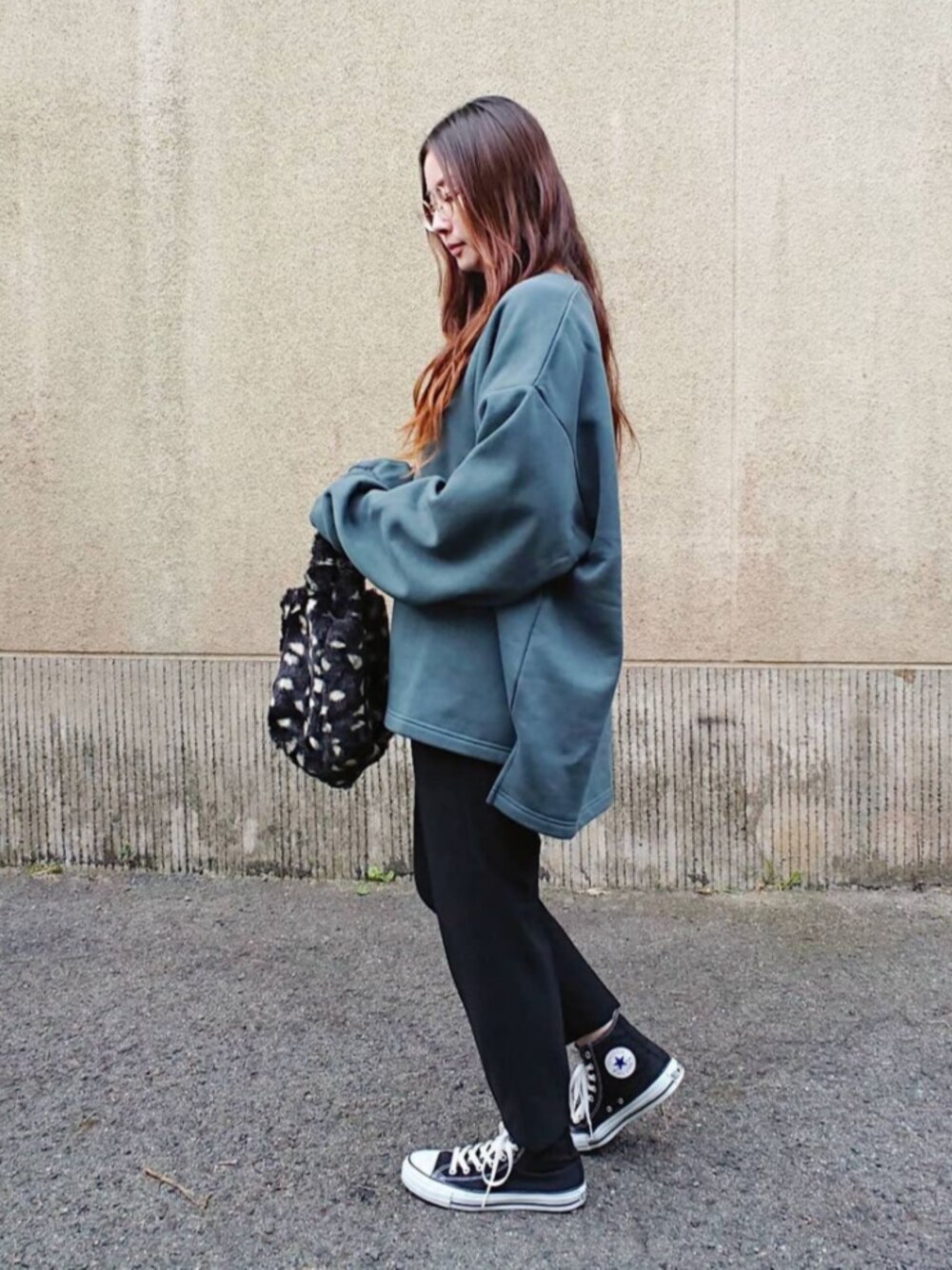 ブラック系のスニーカー、ブラック系のバッグ、グリーン系のスウェットを着用したレディースの冬コーディネートの1枚目の写真