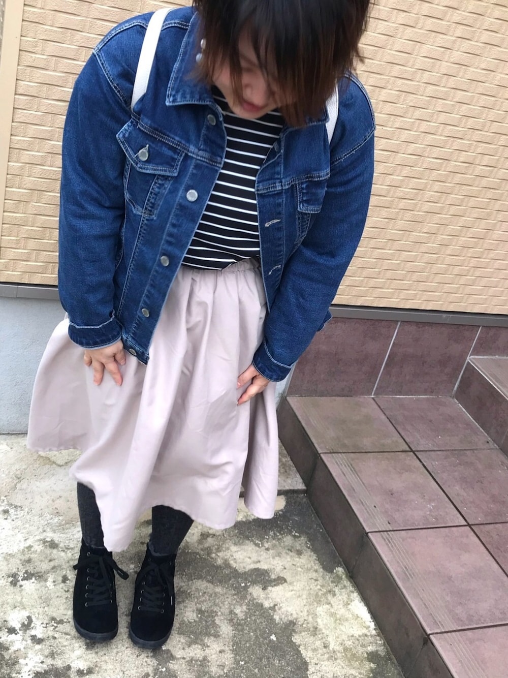 ブルー系のデニムジャケット、ブラック系のTシャツ/カットソー、ベージュ系のスカートを着用したレディースの春コーディネートの1枚目の写真