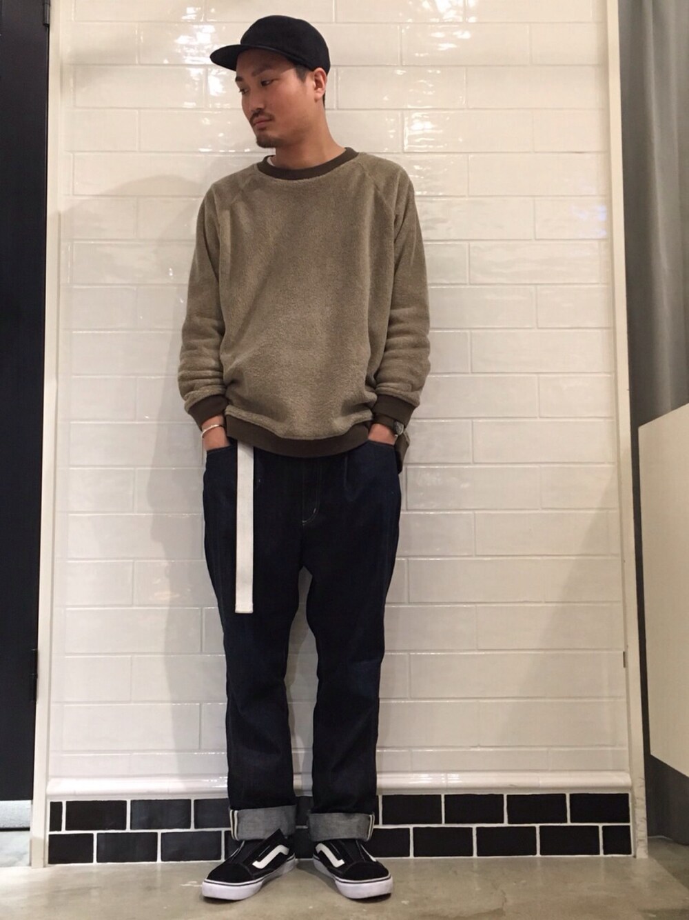 ブルー系のデニムパンツ、ベージュ系のスウェット、ブラック系のキャップを着用したメンズの冬コーディネートの1枚目の写真
