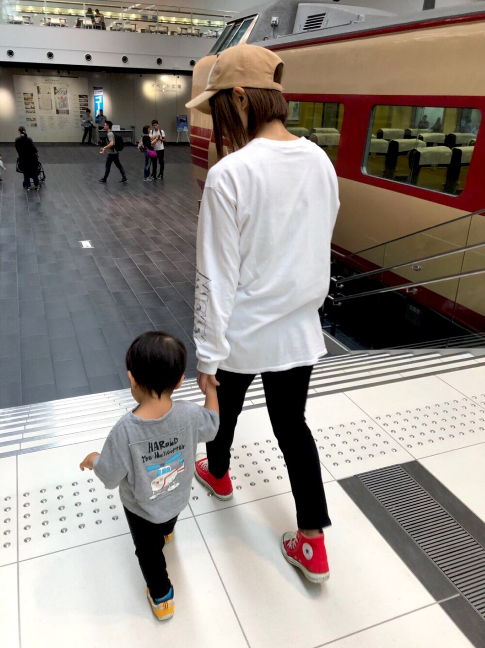 ホワイト系のTシャツ/カットソー、レッド系のスニーカー、ベージュ系のキャップを着用したレディースの秋コーディネートの1枚目の写真