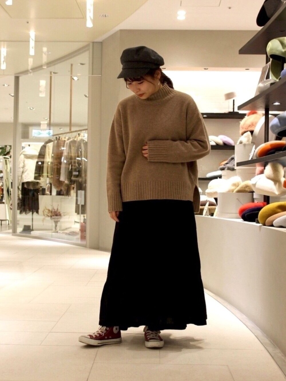 ベージュ系のニット/セーター、ブラック系のスカート、レッド系のスニーカーを着用したレディースの冬コーディネートの1枚目の写真