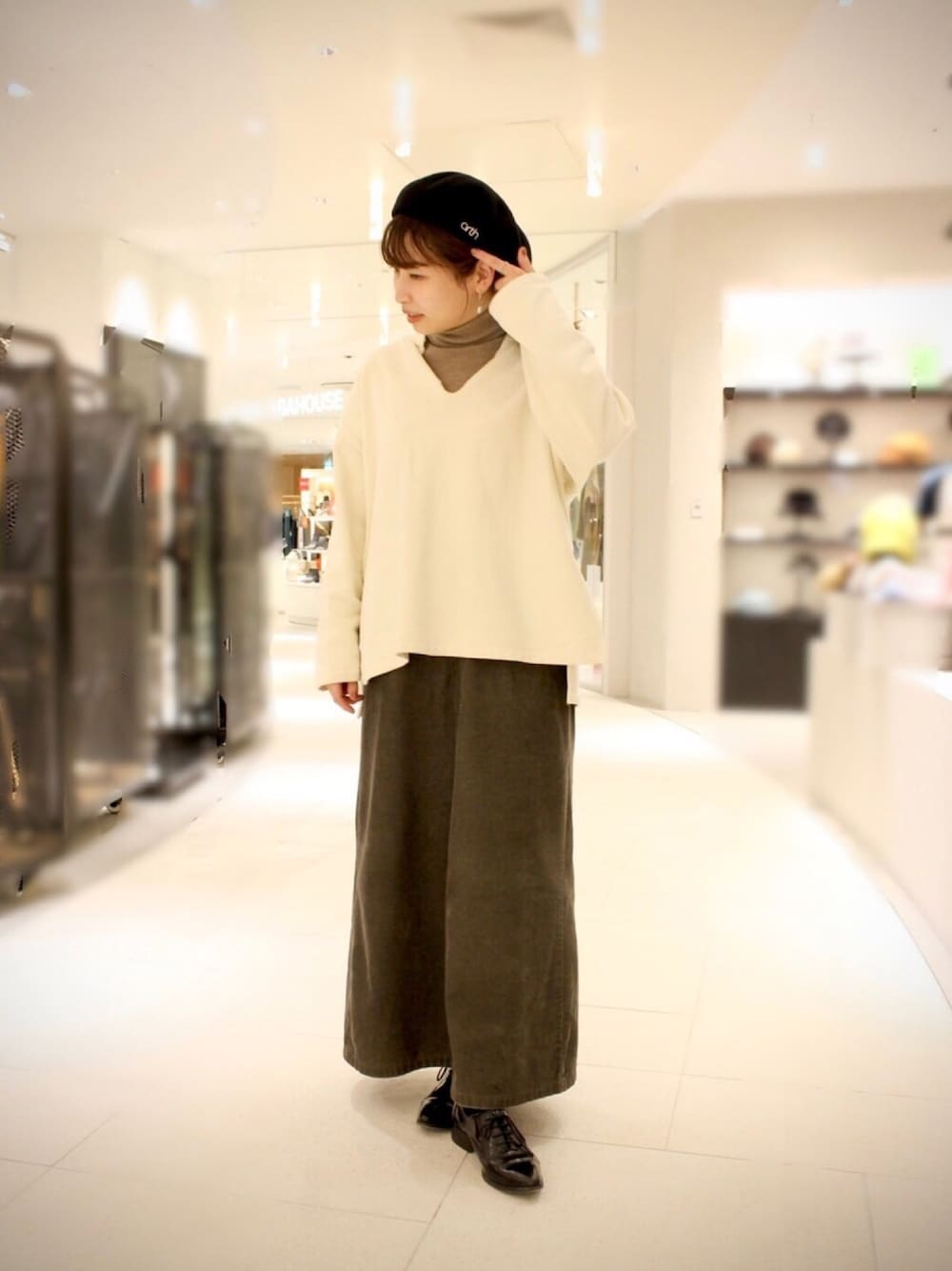 ブラウン系のニット/セーター、グリーン系のスカート、ホワイト系のTシャツ/カットソーを着用したレディースの冬コーディネートの1枚目の写真