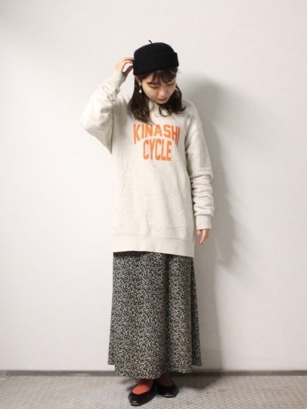 ベージュ系のスウェット、ブラック系のスカート、ブラック系のパンプスを着用したレディースの冬コーディネートの1枚目の写真