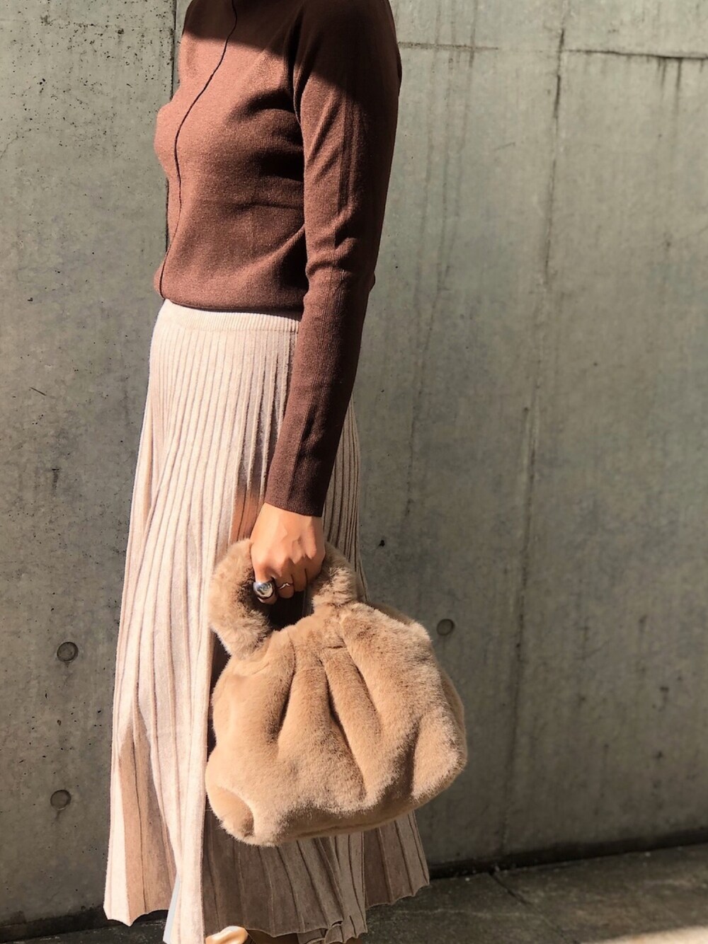 ベージュ系のハンドバッグ、ブラウン系のニット/セーター、ホワイト系のスカートを着用したレディースの秋コーディネートの1枚目の写真
