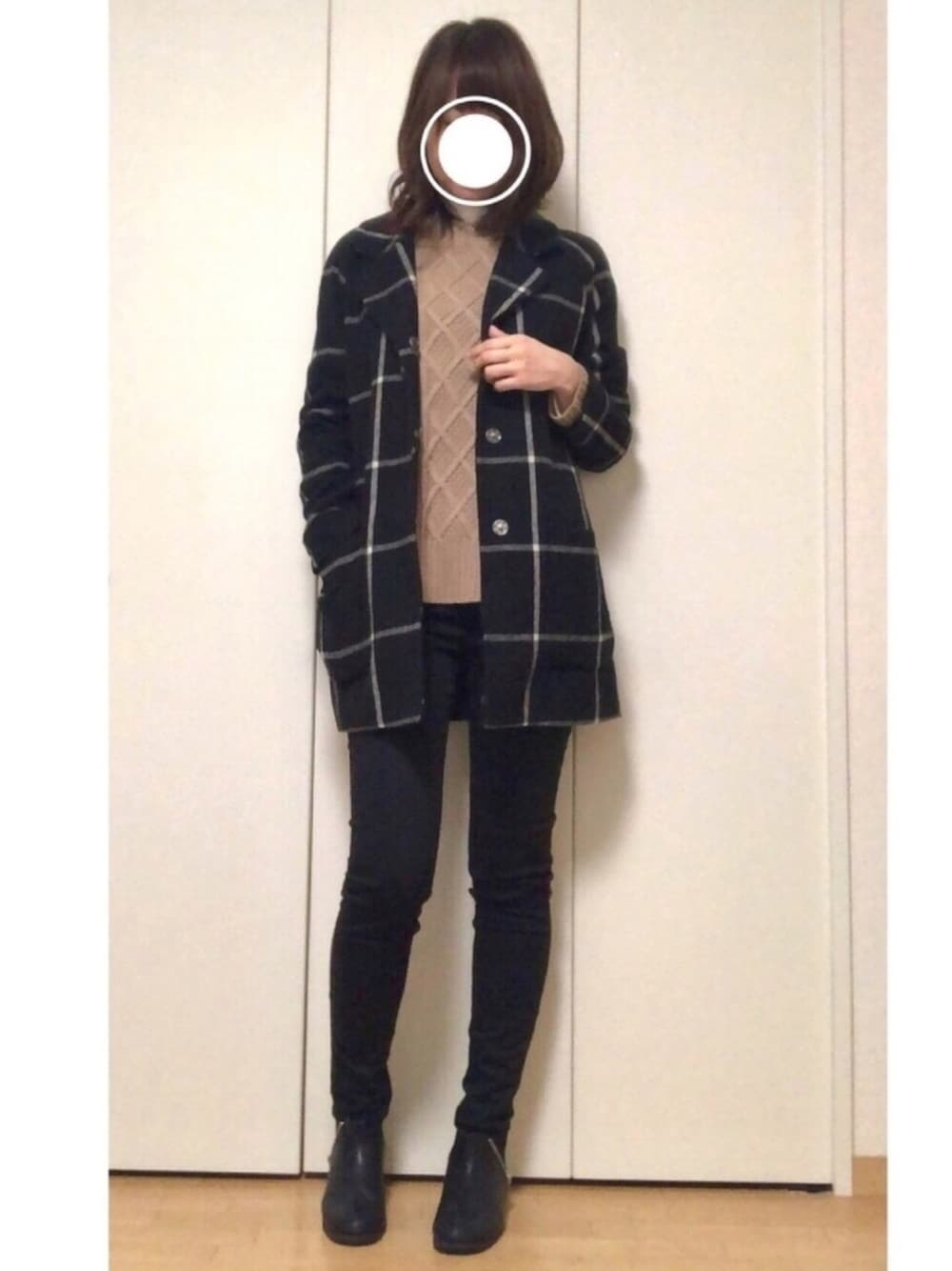 ブラック系のチェスターコート、ブラウン系のニット/セーター、ホワイト系のTシャツ/カットソーを着用したレディースの冬コーディネートの1枚目の写真