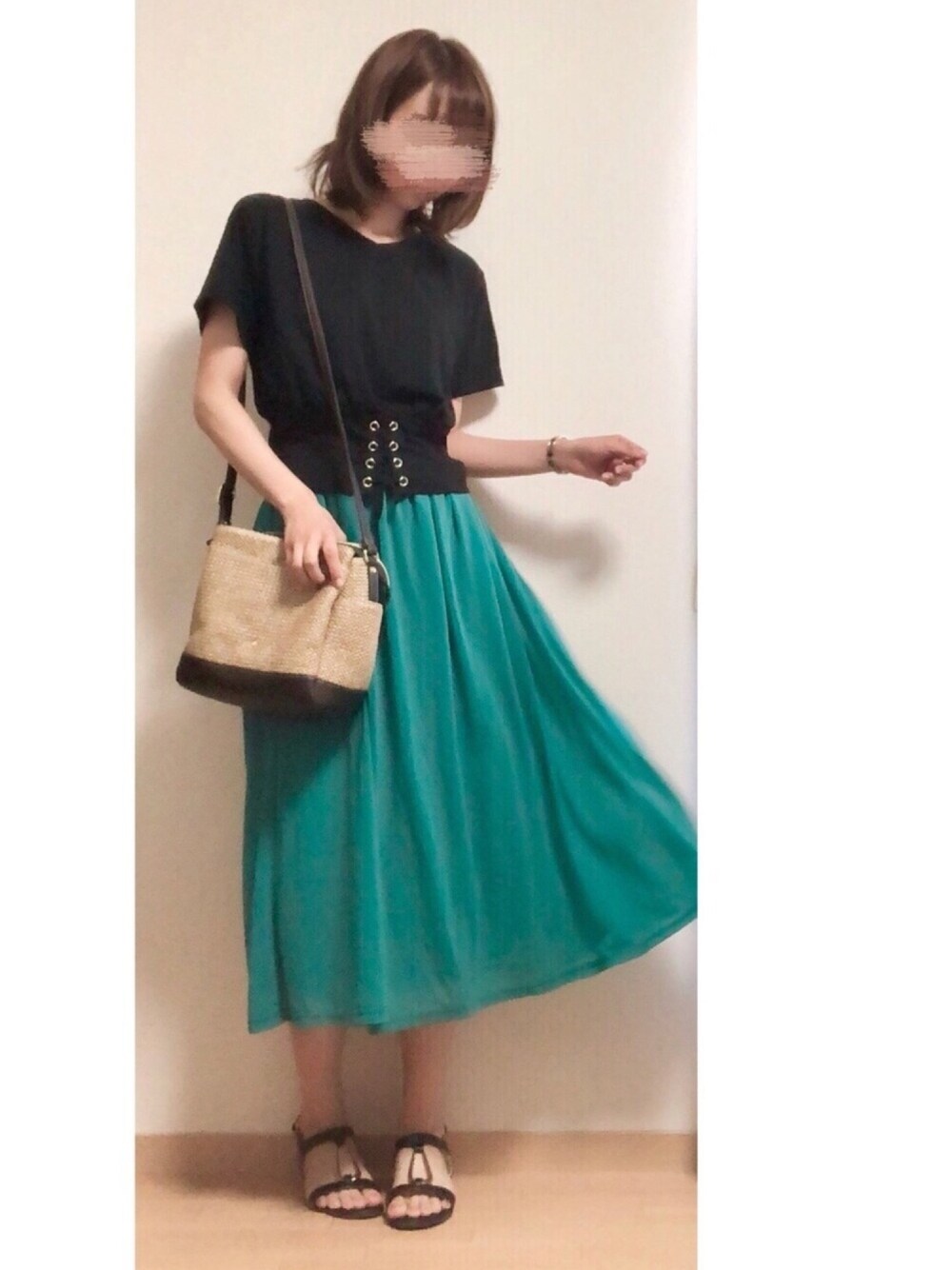 ブラック系のTシャツ/カットソー、グリーン系のスカート、ベージュ系のかごバッグを着用したレディースの春コーディネートの1枚目の写真