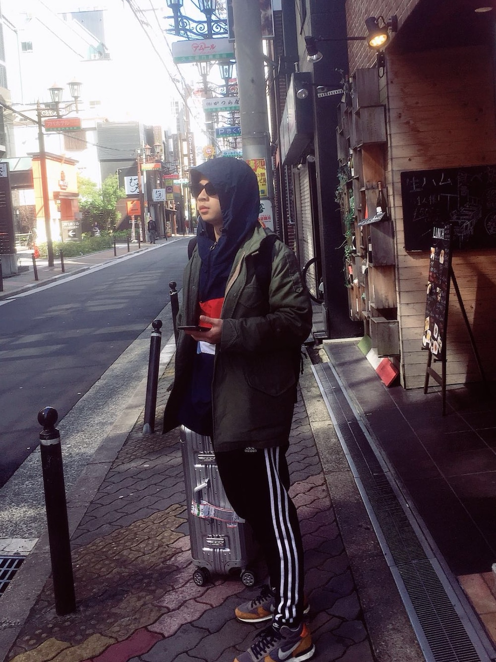 オレンジ系のスニーカー、ブラック系のチノパンツ、グリーン系のミリタリージャケットを着用したメンズの春コーディネートの1枚目の写真