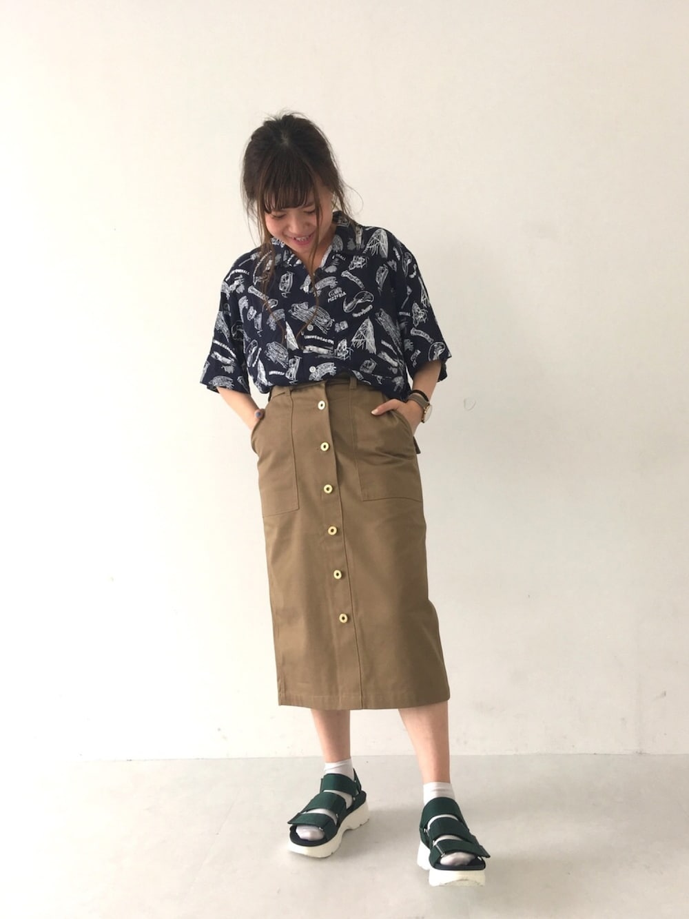 グリーン系のスカート、グリーン系のサンダル、ブルー系のシャツ/ブラウスを着用したレディースの春コーディネートの1枚目の写真