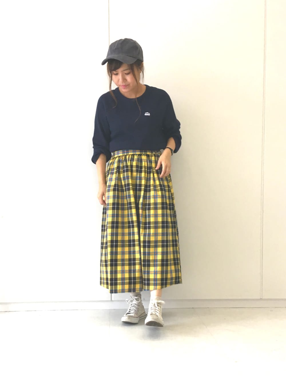 ブルー系のTシャツ/カットソー、イエロー系のスカート、グレー系のキャップを着用したレディースの秋コーディネートの1枚目の写真