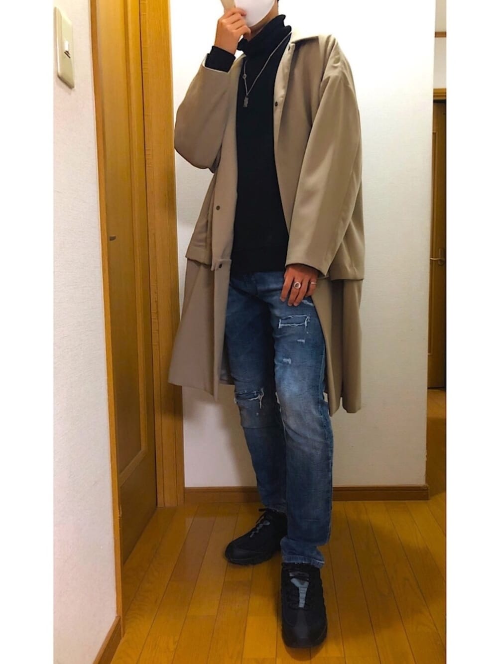 ブラック系のTシャツ/カットソー、ベージュ系のチェスターコート、ブルー系のデニムパンツを着用したメンズの冬コーディネートの1枚目の写真