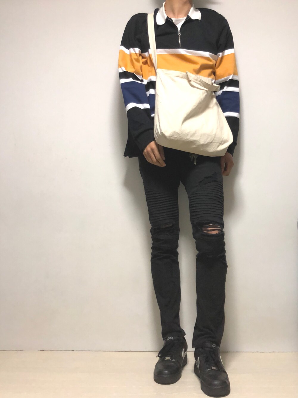 ブラック系のポロシャツ、ベージュ系のトートバッグ、ブラック系のデニムパンツを着用したメンズの秋コーディネートの1枚目の写真