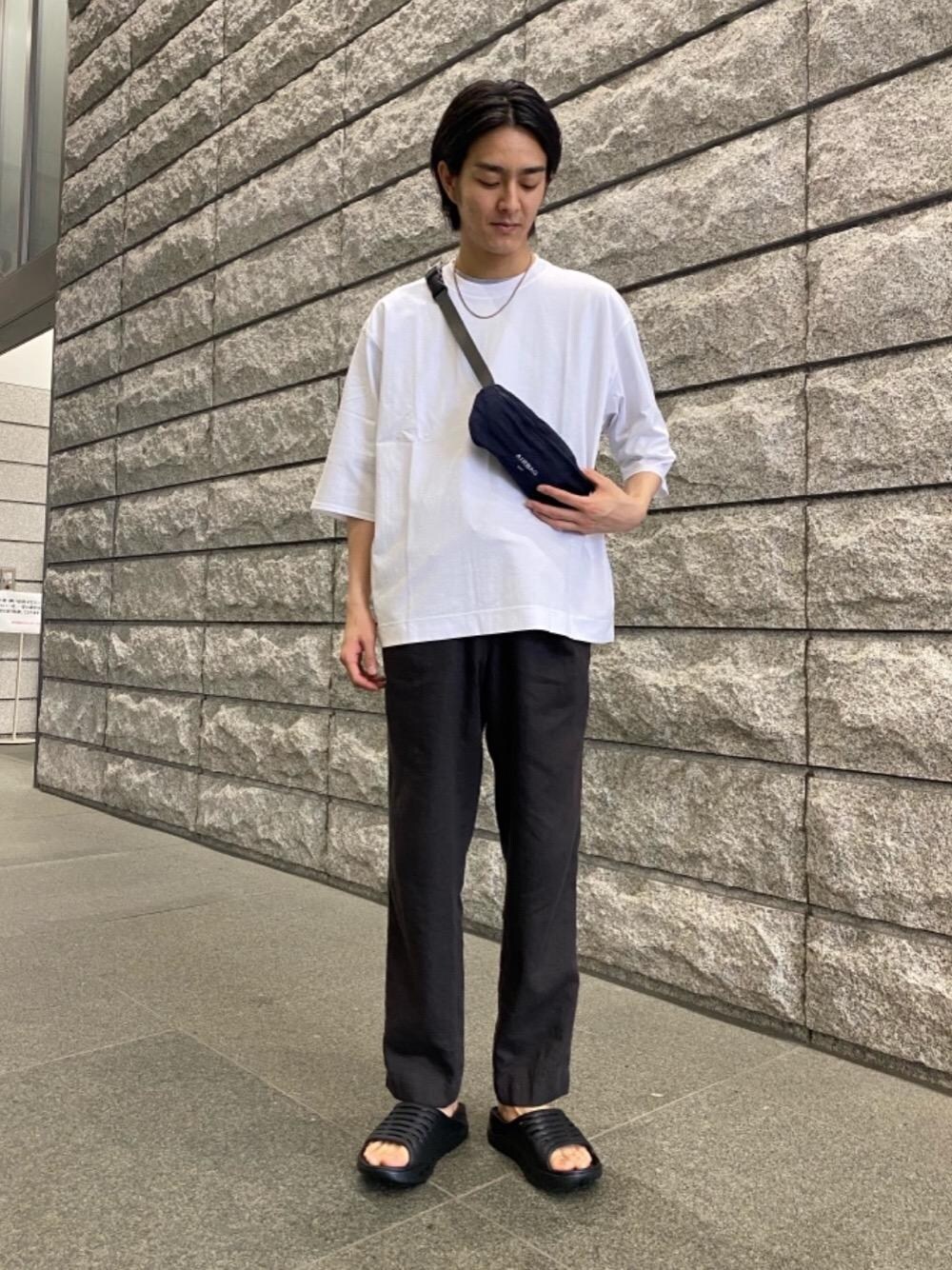 ブラック系のサンダル、ブルー系のボディバッグ/ウエストポーチ、ホワイト系のTシャツ/カットソーを着用したメンズの春コーディネートの1枚目の写真