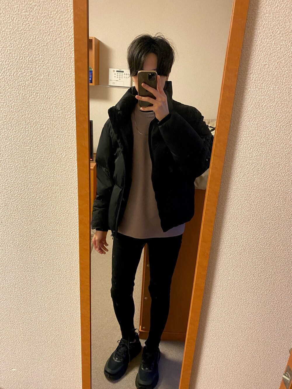 ブラック系のダウンジャケット/コート、ベージュ系のニット/セーター、ブラック系のデニムパンツを着用したメンズの秋コーディネートの1枚目の写真