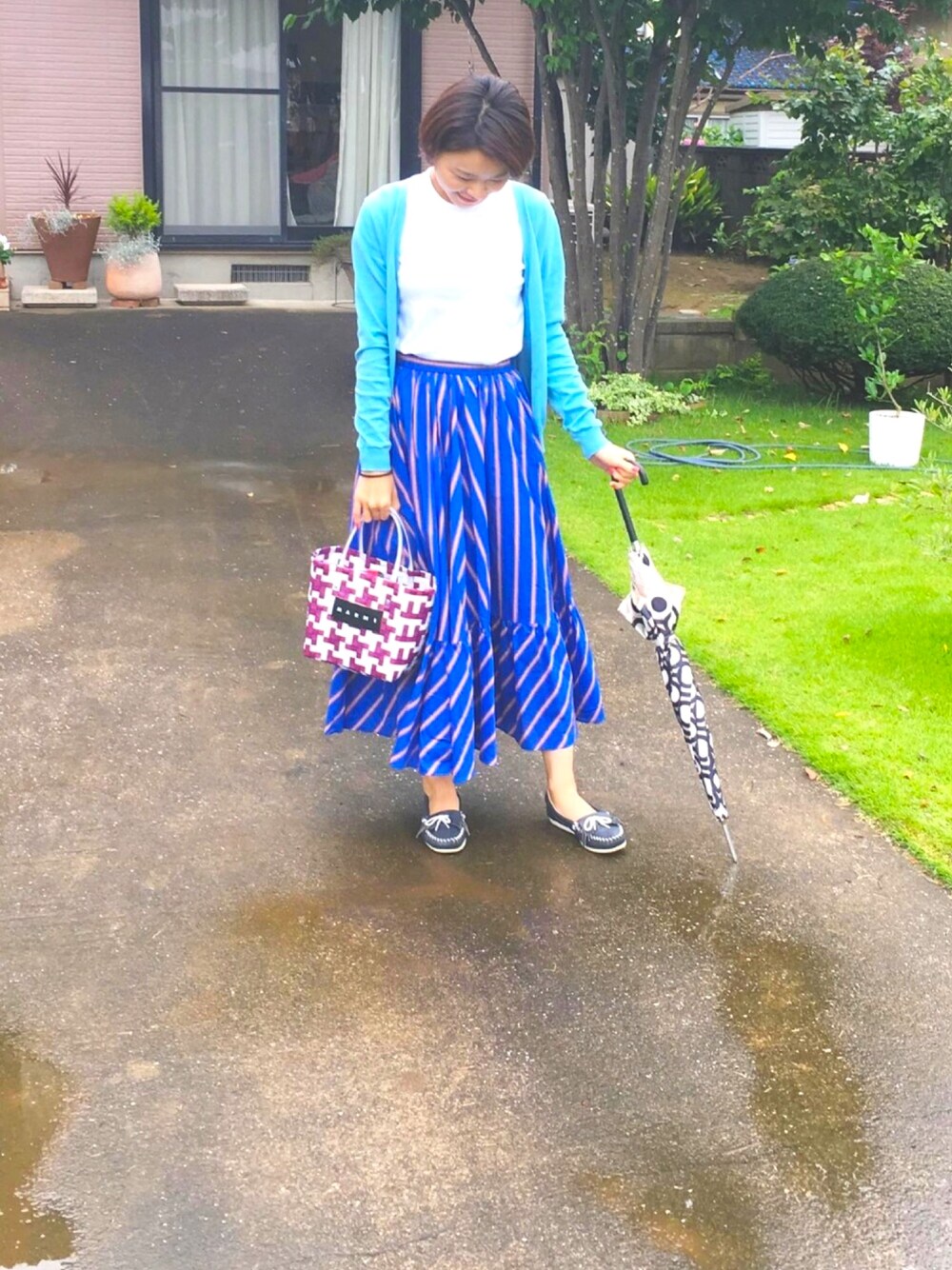 レッド系のトートバッグ、ブルー系のその他シューズ、ブルー系のカーディガン/ボレロを着用したレディースの夏コーディネートの1枚目の写真