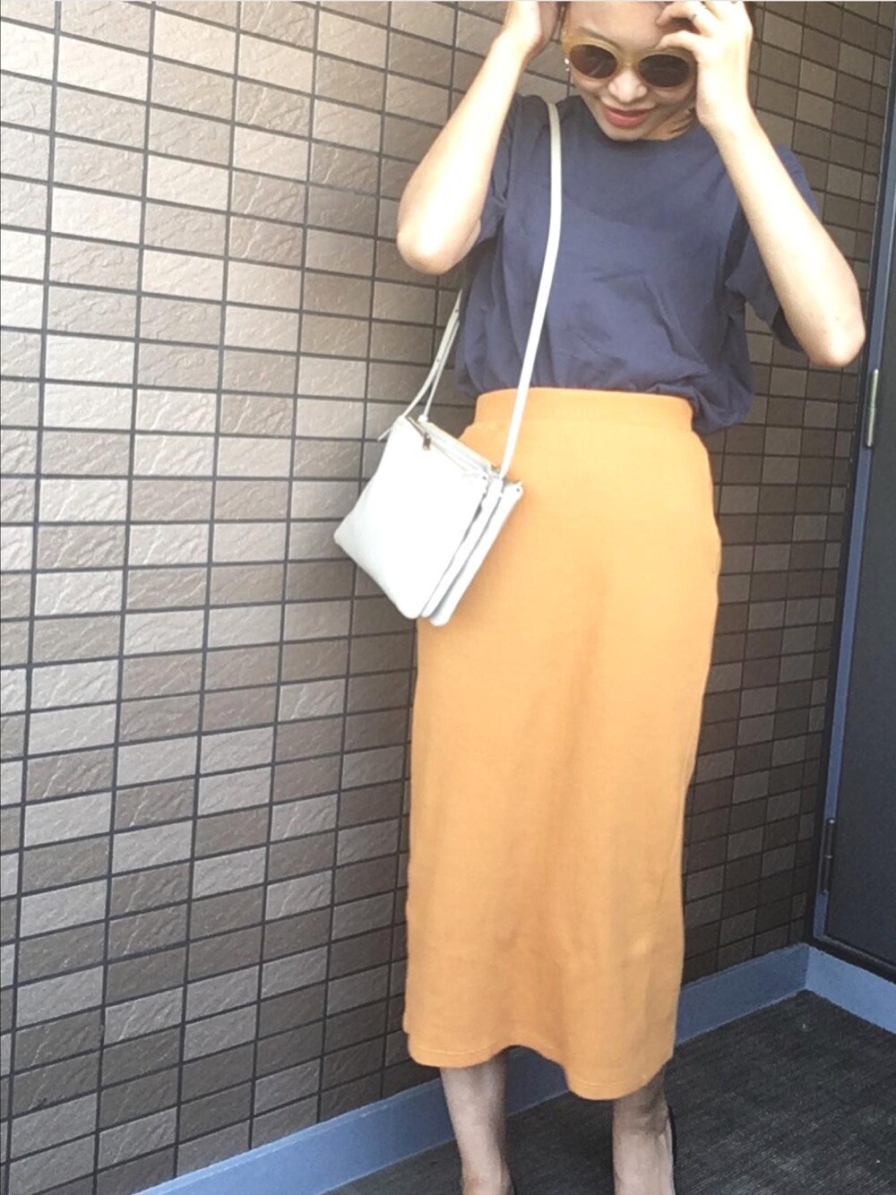 ベージュ系のショルダーバッグ、イエロー系のスカート、グリーン系のTシャツ/カットソーを着用したレディースの夏コーディネートの1枚目の写真