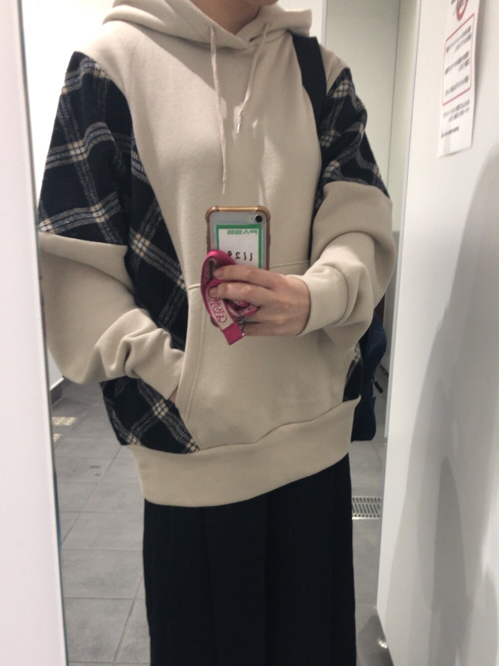 ベージュ系のパーカー、ブラック系のスニーカー、ブラック系のパンツを着用したレディースの冬コーディネートの1枚目の写真