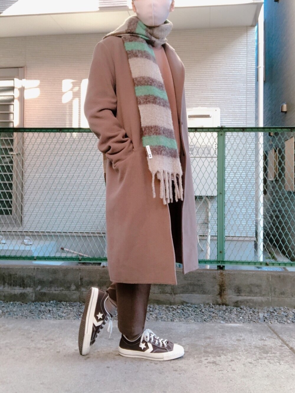 ブラウン系のスウェット、ベージュ系のチェスターコート、ブラウン系のスラックスを着用したメンズの冬コーディネートの1枚目の写真