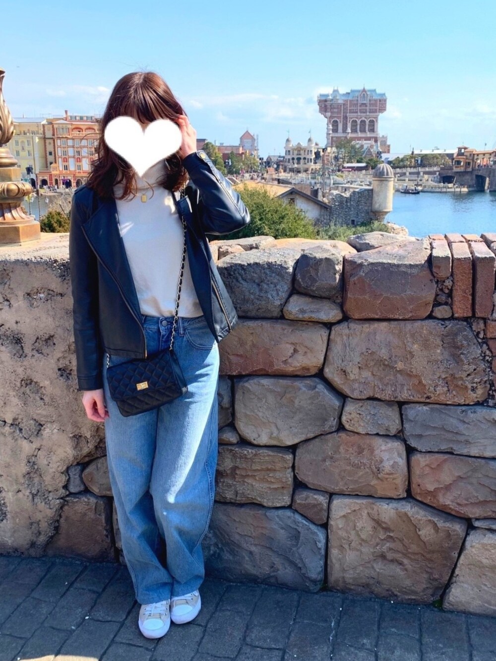 ホワイト系のデニムパンツ、ホワイト系のニット/セーター、ブラック系のショルダーバッグを着用したレディースの春コーディネートの1枚目の写真