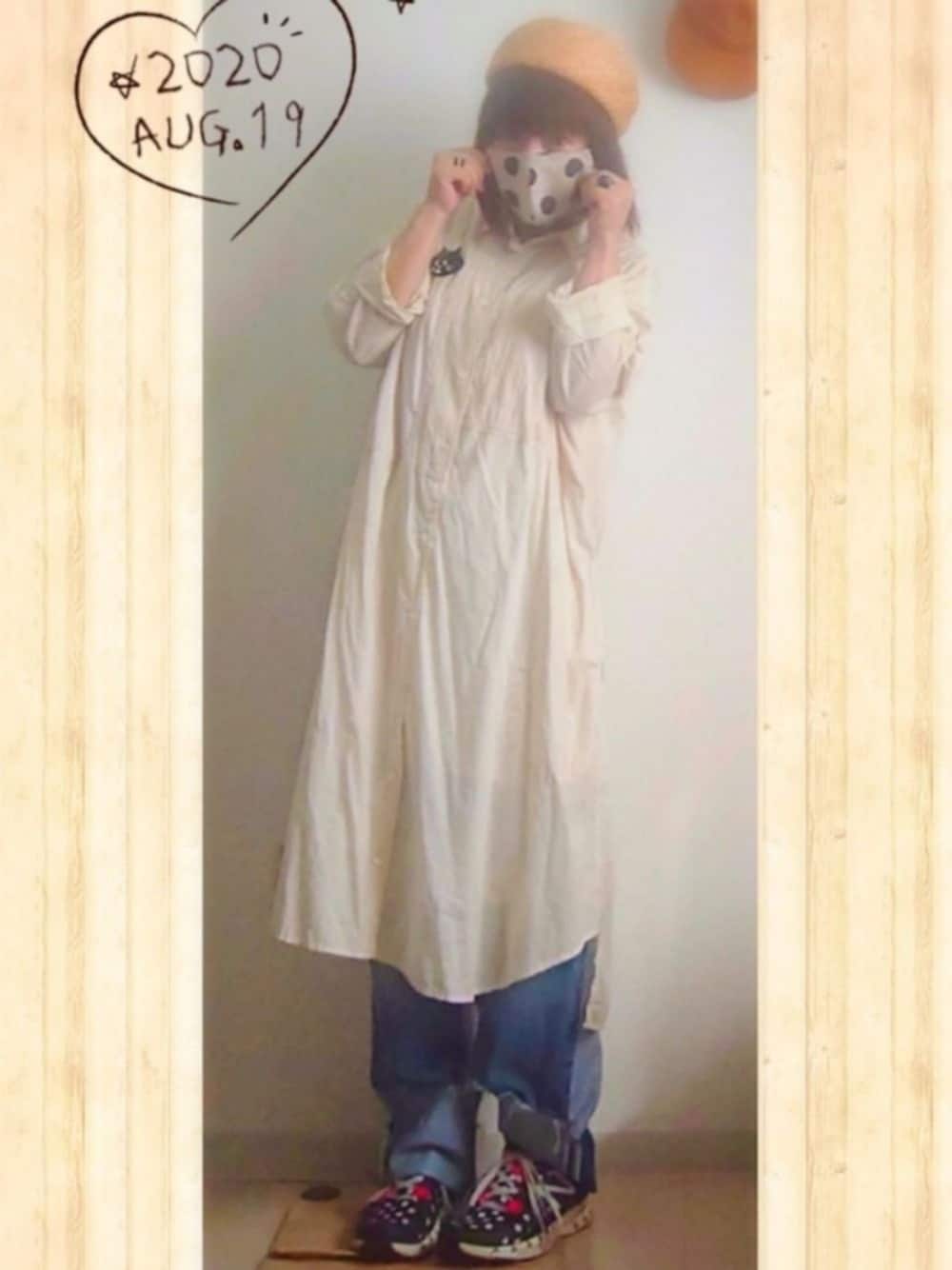 ホワイト系のシャツワンピース、ブルー系のデニムパンツ、ブラック系のスニーカーを着用したレディースの夏コーディネートの1枚目の写真