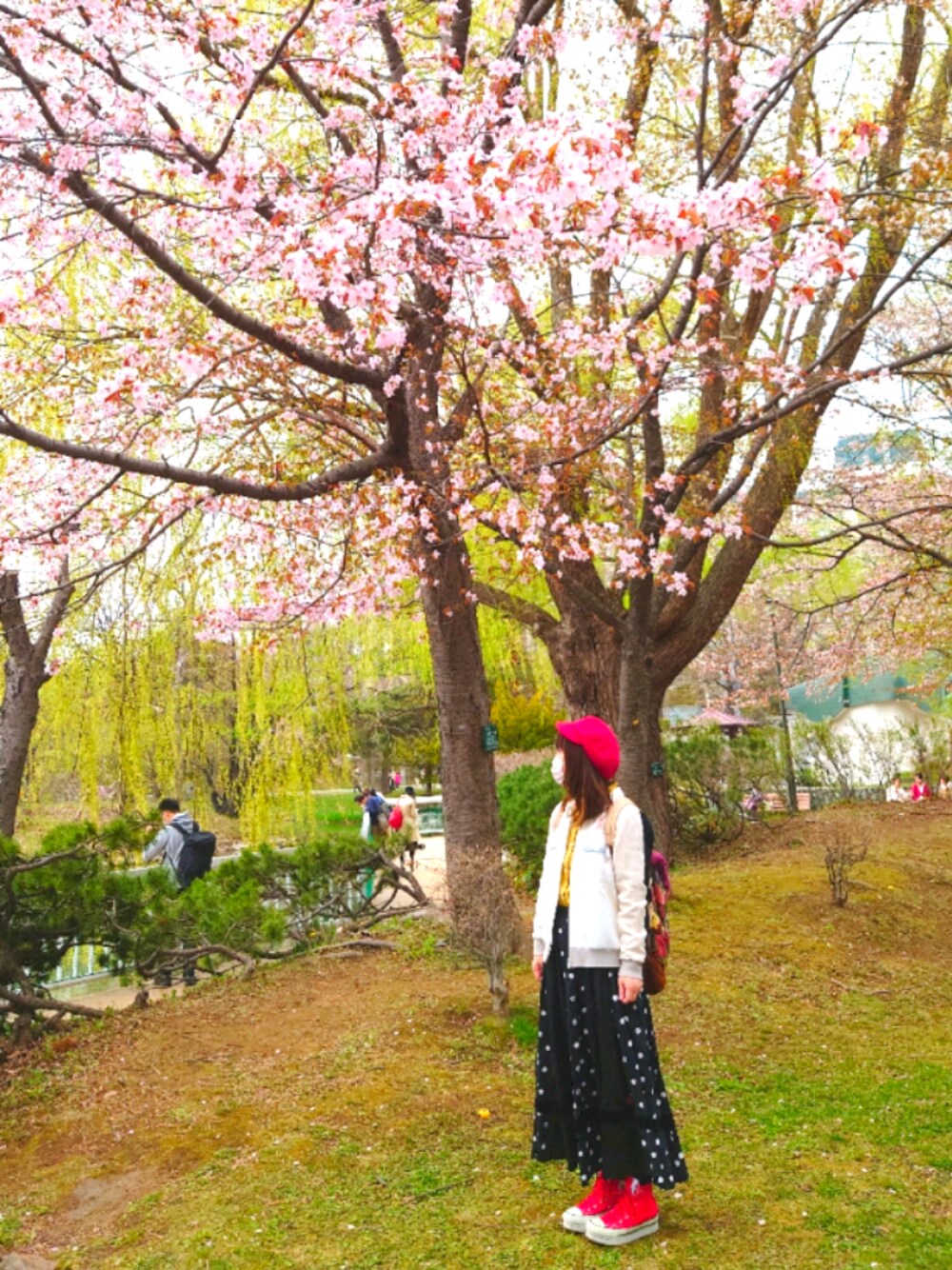 レッド系のバックパック/リュック、レッド系のスニーカー、ベージュ系のスタジャンを着用したレディースの春コーディネートの1枚目の写真