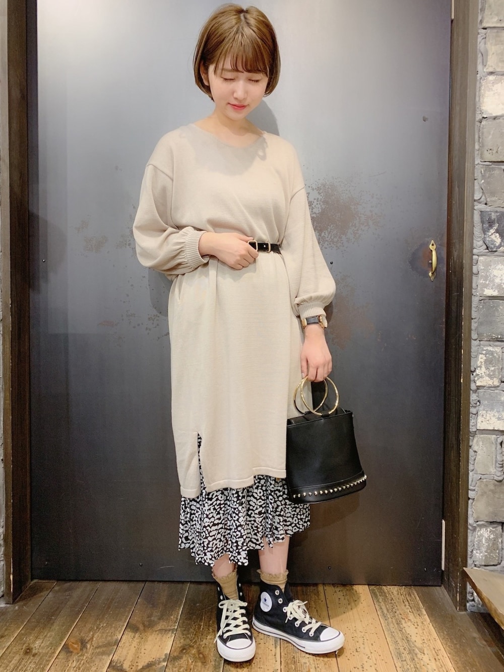 ブラック系のスニーカー、ブラック系のスカート、ブラック系のハンドバッグを着用したレディースの冬コーディネートの1枚目の写真