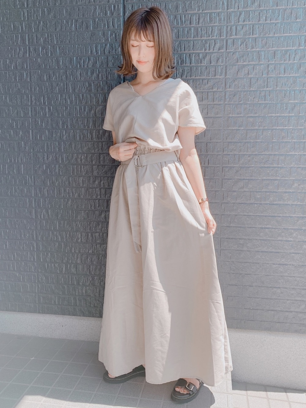 ベージュ系のワンピース、ブラック系のサンダルを着用したレディースの秋コーディネートの1枚目の写真