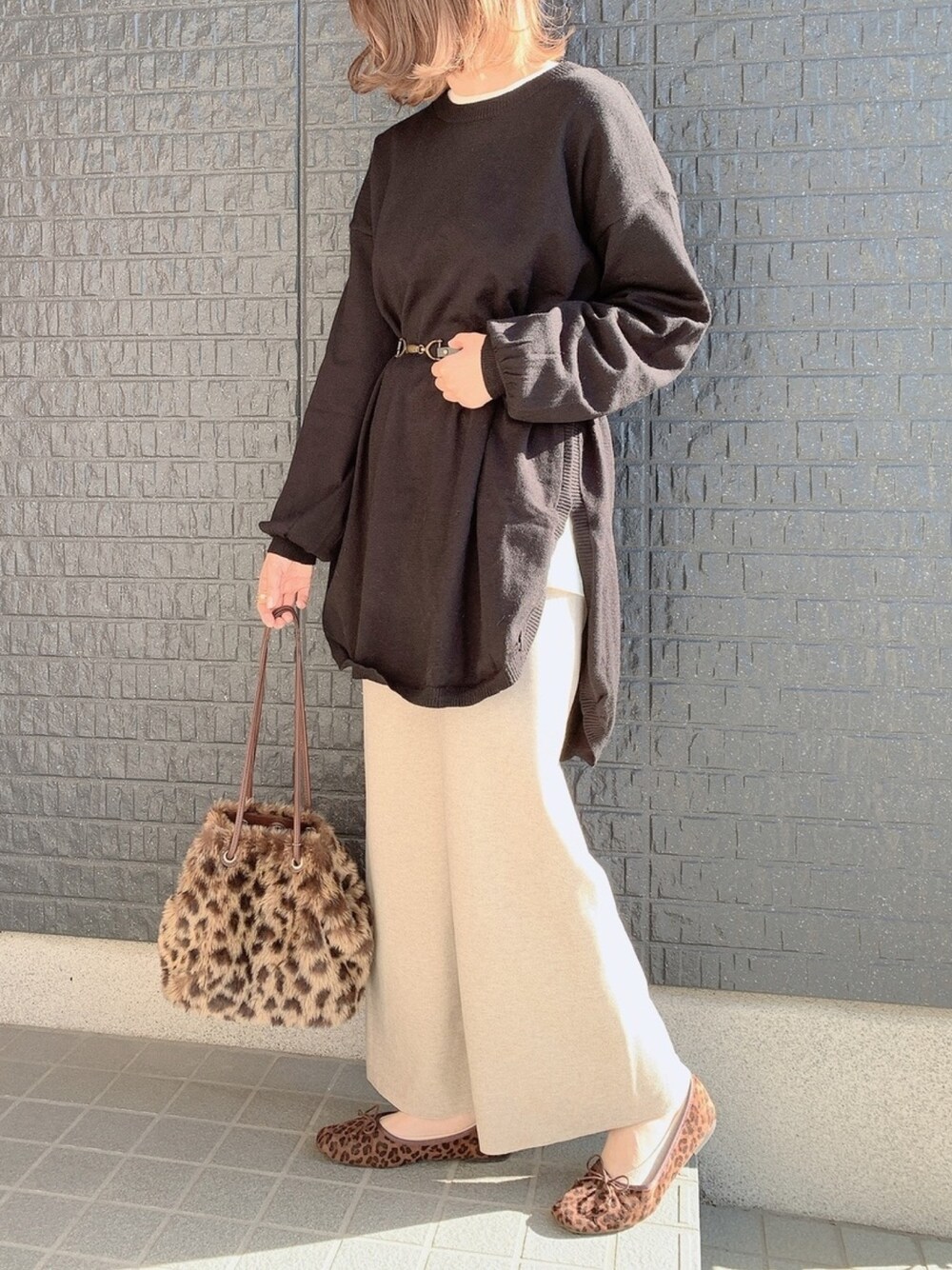 ブラック系のチュニック、ホワイト系のTシャツ/カットソー、ベージュ系のパンツを着用したレディースの冬コーディネートの1枚目の写真