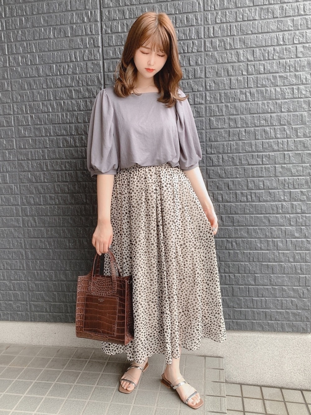 グレー系のTシャツ/カットソー、ベージュ系のスカート、ベージュ系のサンダルを着用したレディースの夏コーディネートの1枚目の写真