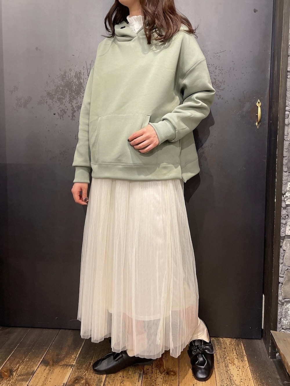 ホワイト系のスカート、グリーン系のパーカー、ホワイト系のTシャツ/カットソーを着用したレディースの冬コーディネートの1枚目の写真