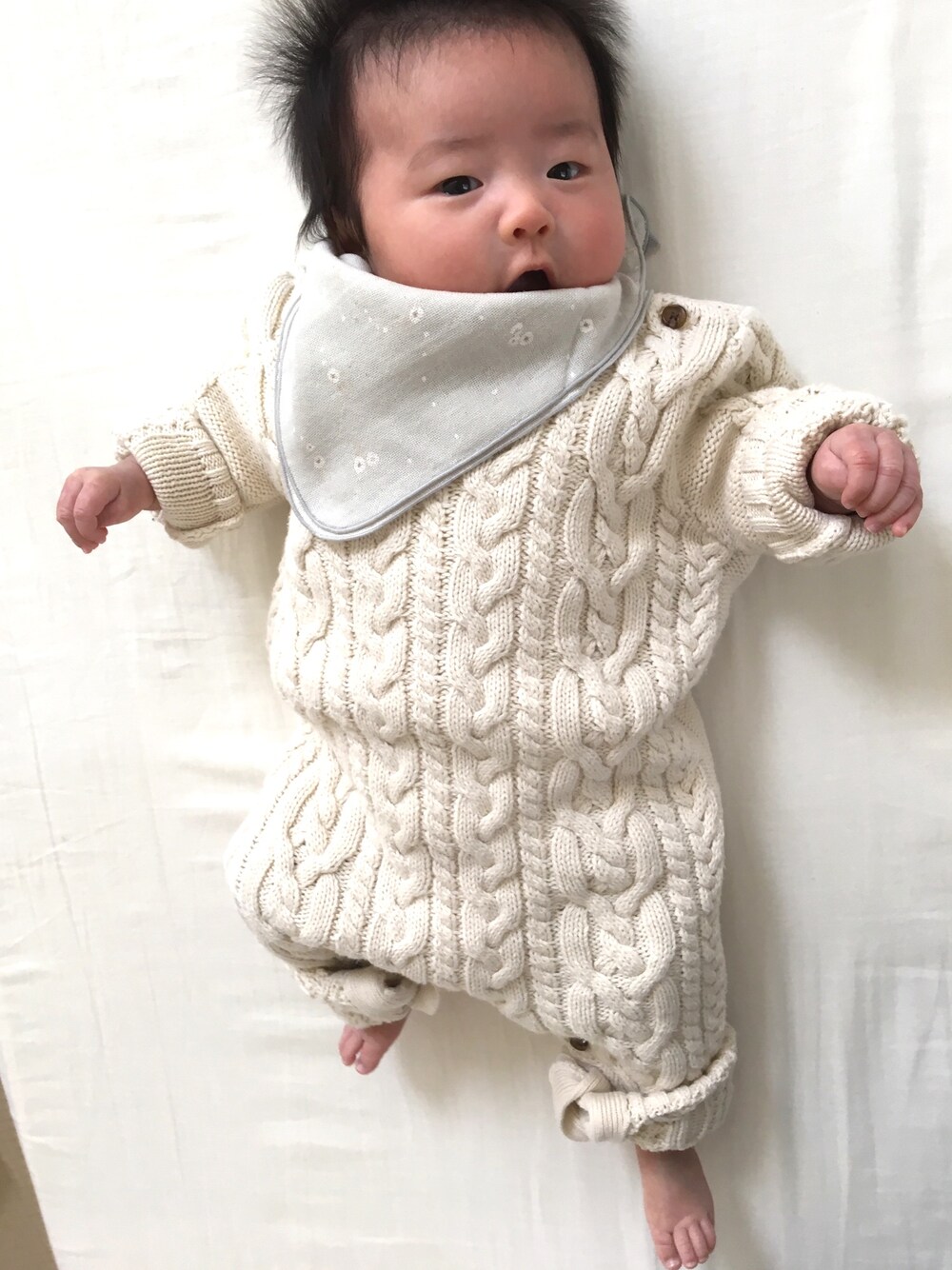 ベージュ系のロンパース、グレー系のスタイ/よだれかけを着用したレディースの冬コーディネートの1枚目の写真