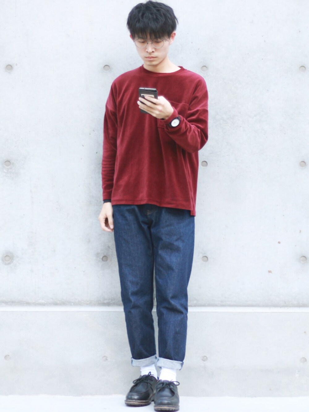 レッド系のスウェット、ブルー系のデニムパンツ、ブラック系のブーツを着用したメンズの秋コーディネートの1枚目の写真