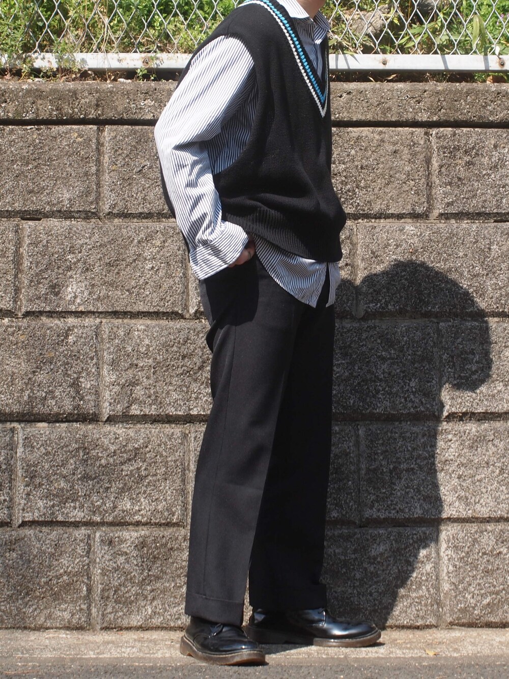 ブラック系のチノパンツ、ブラック系のベスト、ブラック系のトップスを着用したメンズの春コーディネートの1枚目の写真