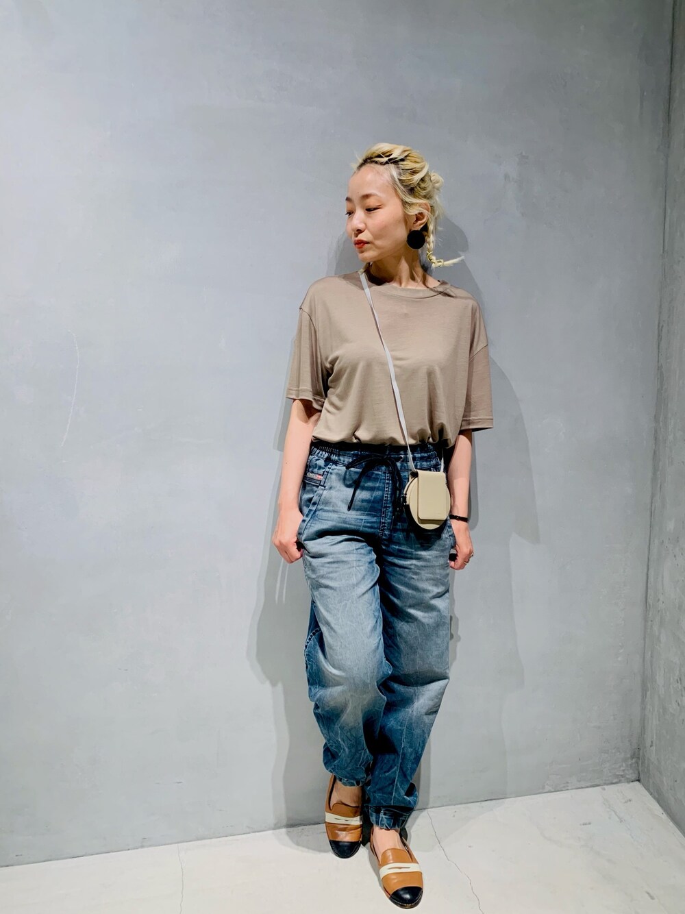 ベージュ系のTシャツ/カットソー、ベージュ系のショルダーバッグ、ブルー系のデニムパンツを着用したレディースの夏コーディネートの1枚目の写真