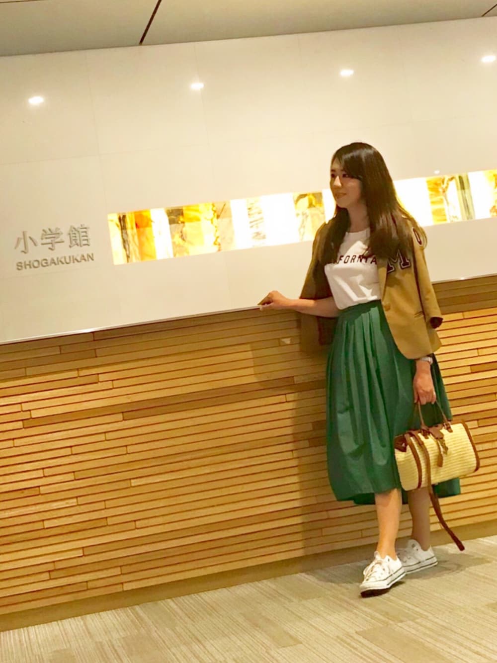 グリーン系のスカート、ホワイト系のスニーカー、ホワイト系のTシャツ/カットソーを着用したレディースの春コーディネートの1枚目の写真