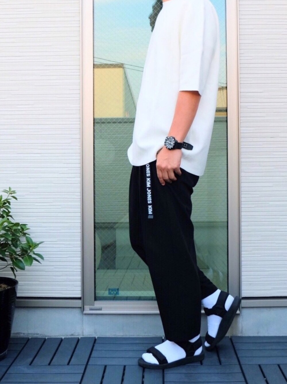 ホワイト系のニット/セーター、ブラック系のスラックス、ブラック系のサンダルを着用したメンズの春コーディネートの1枚目の写真