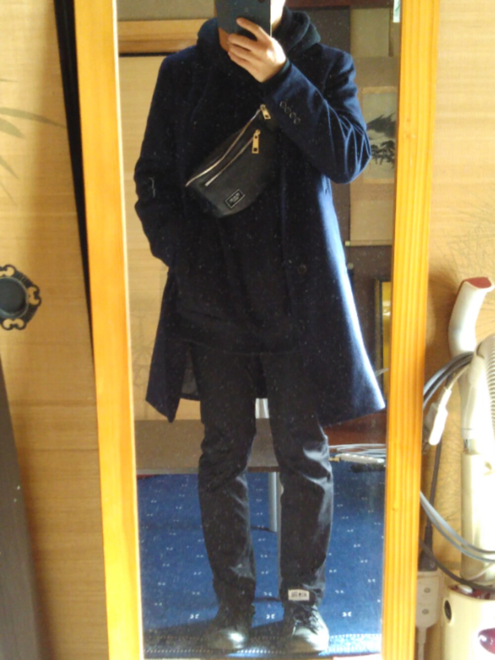 ブラック系のパーカー、ブルー系のチェスターコート、ブラック系のデニムパンツを着用したメンズの冬コーディネートの1枚目の写真