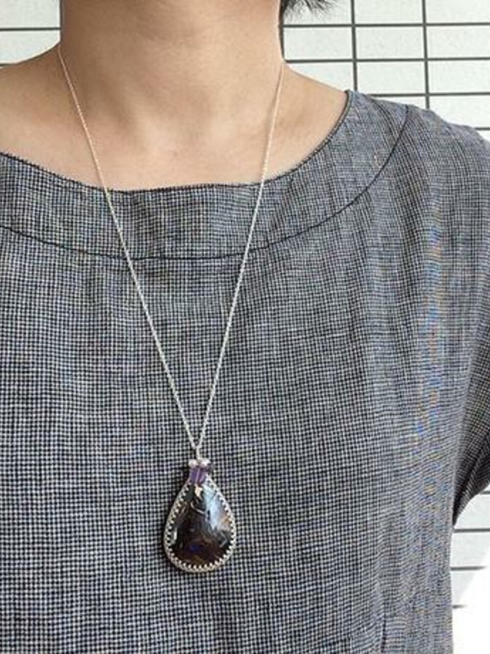 グレー系のチュニック、ブラウン系のネックレスを着用したレディースの冬コーディネートの1枚目の写真