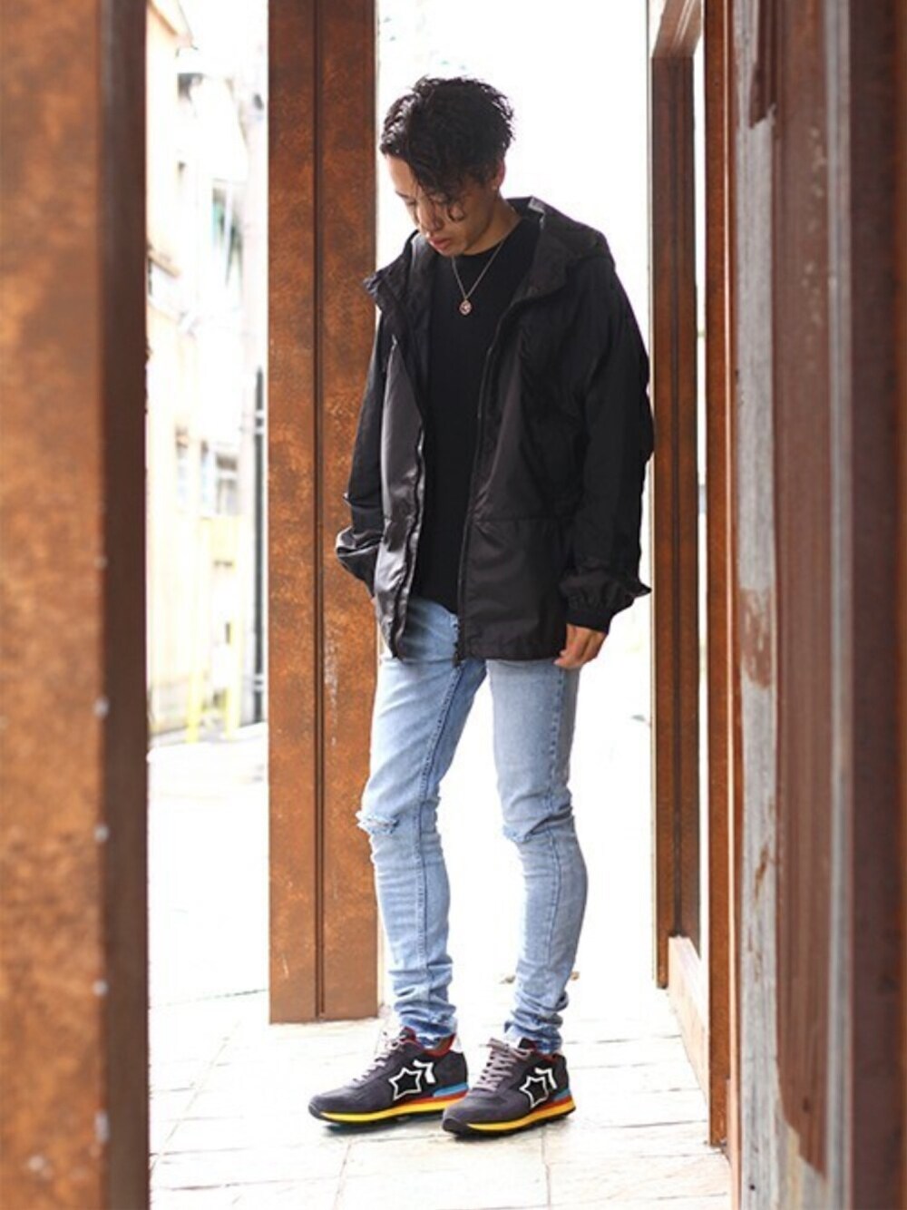 ブラック系のブルゾン、ブルー系のデニムパンツ、グレー系のスニーカーを着用したメンズの秋コーディネートの1枚目の写真