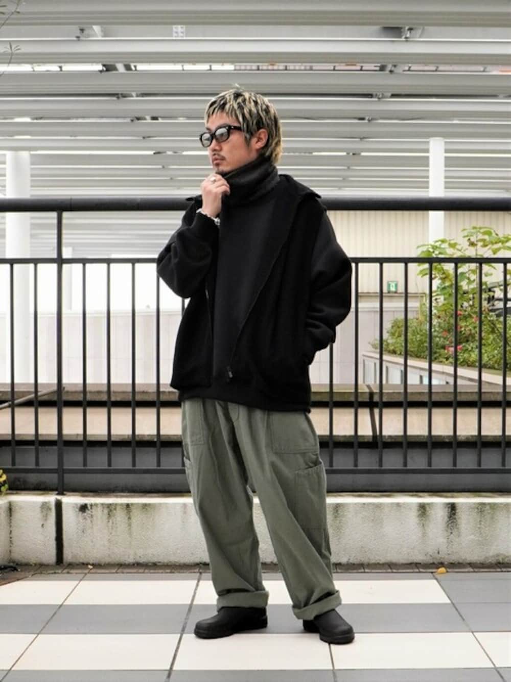 ブラック系のスウェット、ブラック系のベスト、グリーン系のカーゴパンツを着用したメンズの秋コーディネートの1枚目の写真