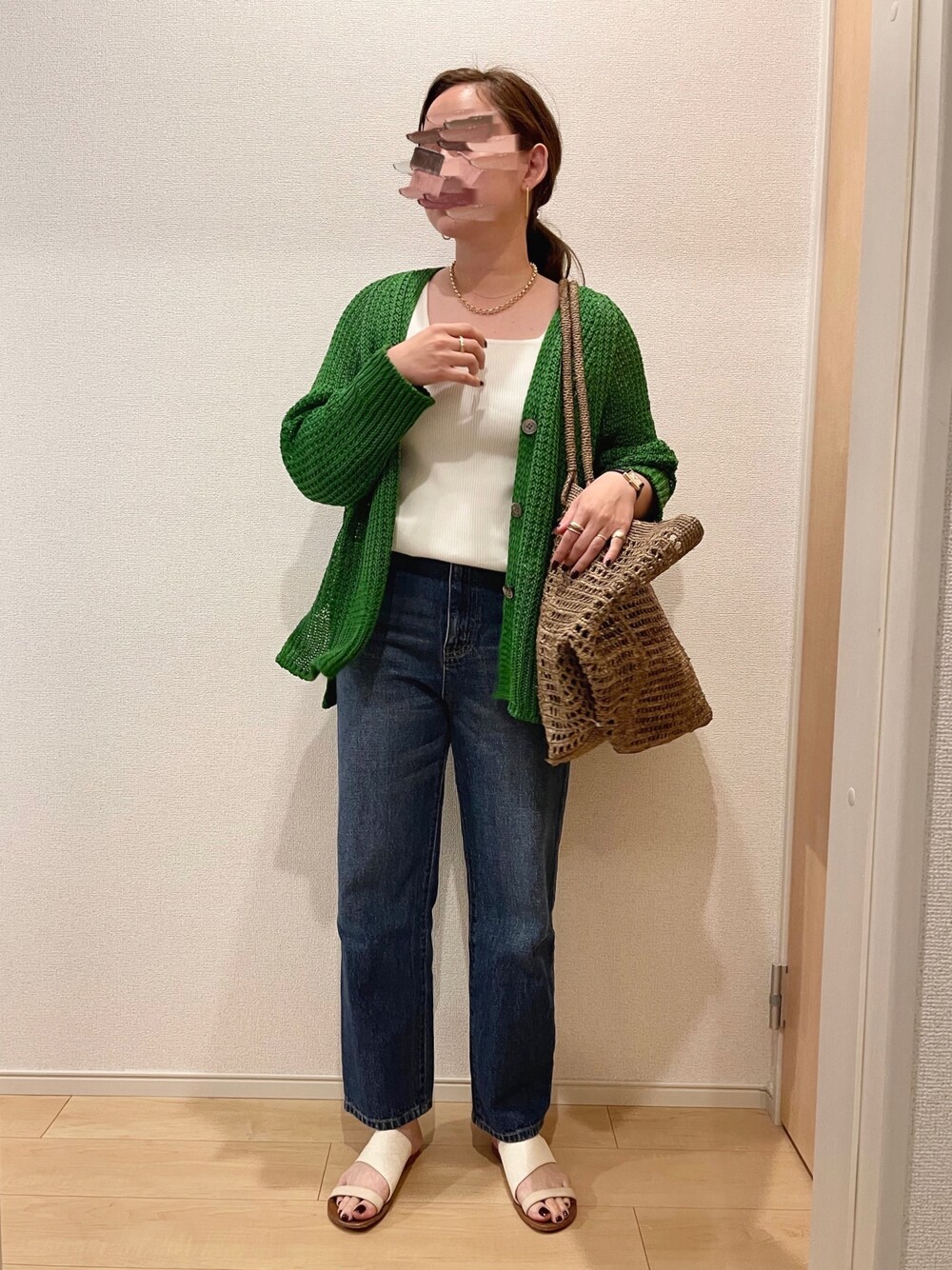 グリーン系のカーディガン/ボレロ、ホワイト系のタンクトップ、ブルー系のデニムパンツを着用したレディースの夏コーディネートの1枚目の写真