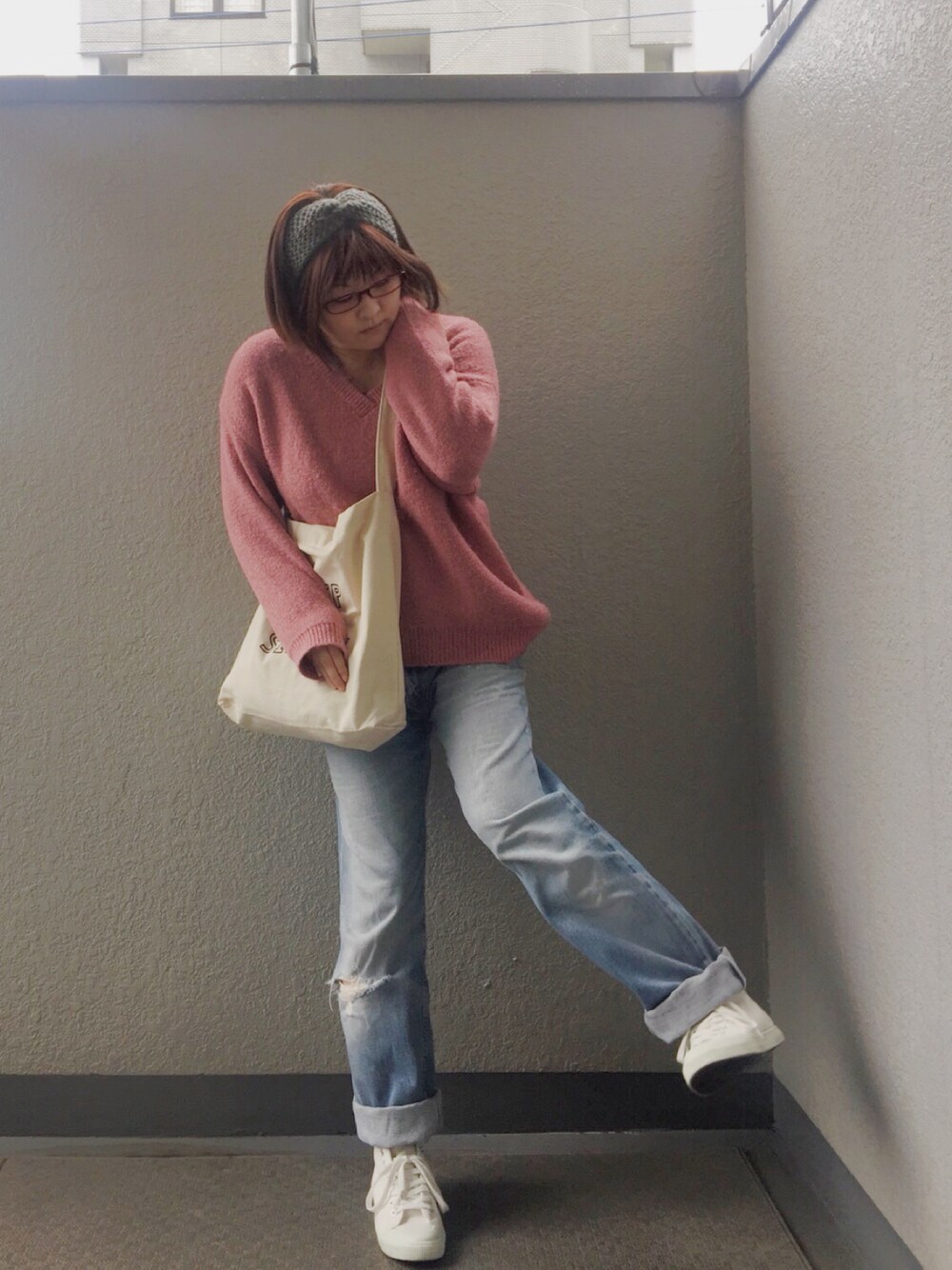 ピンク系のニット/セーター、ホワイト系のショルダーバッグ、ブルー系のデニムパンツを着用したレディースの春コーディネートの1枚目の写真